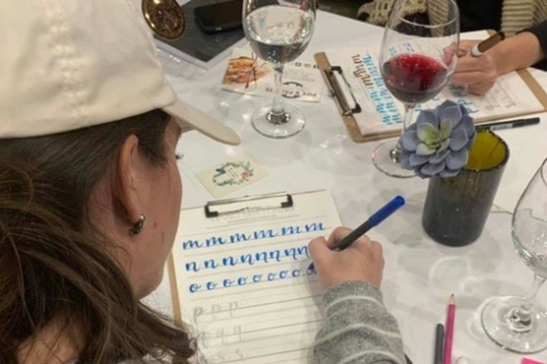 a woman sitting at a table with wine glasses